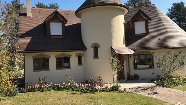 A large, single-story house with a turret and a steeply pitched roof.