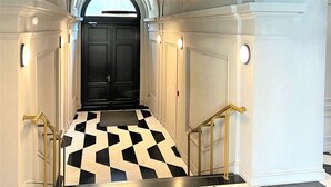 A hallway with a checkered floor, black and white walls, and a black door at the end.