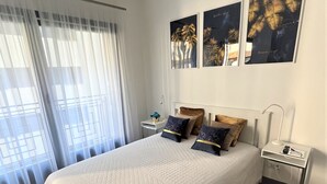 A bedroom with a large bed, a bedside table, a nightstand, and a ceiling light fixture.