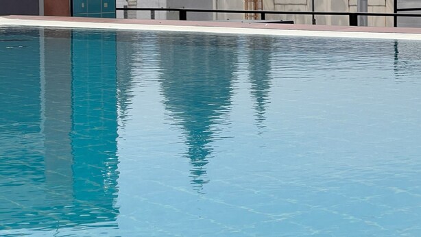 A rooftop pool with a view of a historic building with domes and towers in the background.