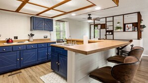 A modern kitchen with blue cabinets, a wooden ceiling, and a bar area with seating.