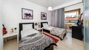 Ein Hotelzimmer mit zwei Betten, einer Gitarre, einem kleinen Tisch und Bildern an der Wand.