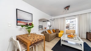 Ein modernes Wohnzimmer mit Essbereich, einer Sofagarnitur, einem Couchtisch und einem Gemälde an der Wand.