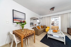 Un salon moderne comprenant un coin repas, un ensemble de canapés, une table basse et un tableau accroché au mur.