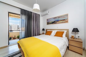 A hotel room with a bed, bedside lamps, a painting, and a view of the outside.