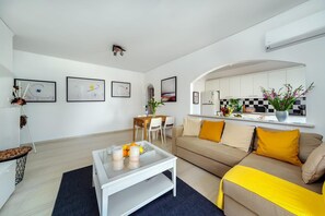 A modern living room with a sofa, coffee table, and artwork on the walls. - Saint Sophias City Stay, Apartment (Iraklio)