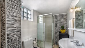 Ein modernes Badezimmer mit einer Duschkabine, einer weißen Badewanne und einem WC.