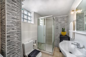 Une salle de bain moderne avec une douche à parois de verre, une baignoire blanche et des toilettes.