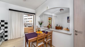 Ein moderner Essbereich mit Tisch für vier Personen, einem Spiegel über dem Tisch und Blick auf den Balkon sowie umliegende Gebäude.