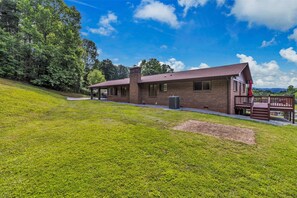 A brick house with a porch, a covered outdoor seating area, and a grassy yard. - Sunset Haven (Marion)