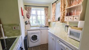 Una cocina compacta con lavadora, microondas y lavabo.