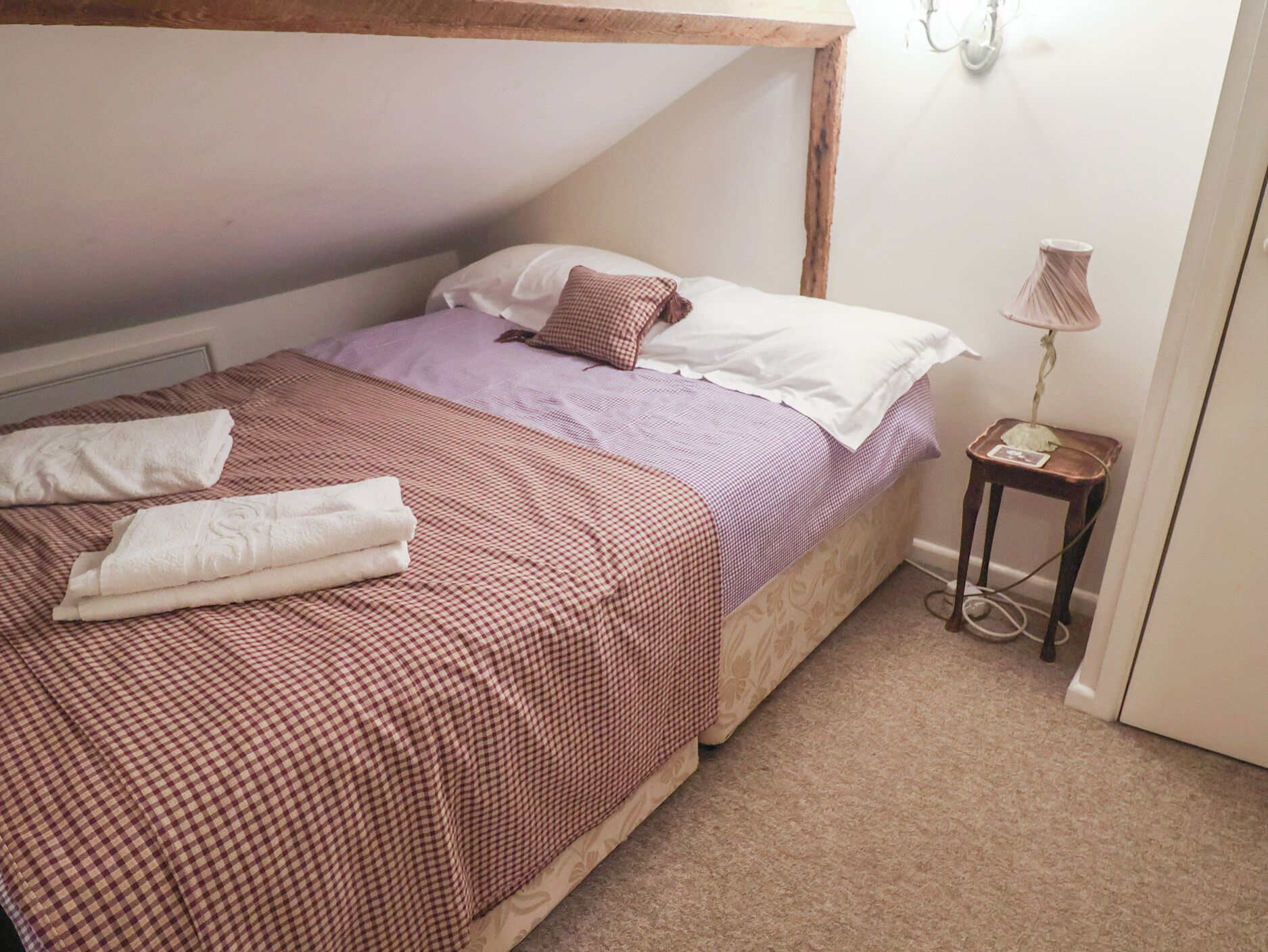 Une chambre à coucher avec un lit, des oreillers, une table de chevet et une lampe.
