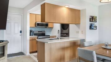 A modern kitchen with wooden cabinets, a central island, and a dining area with a table and chairs.