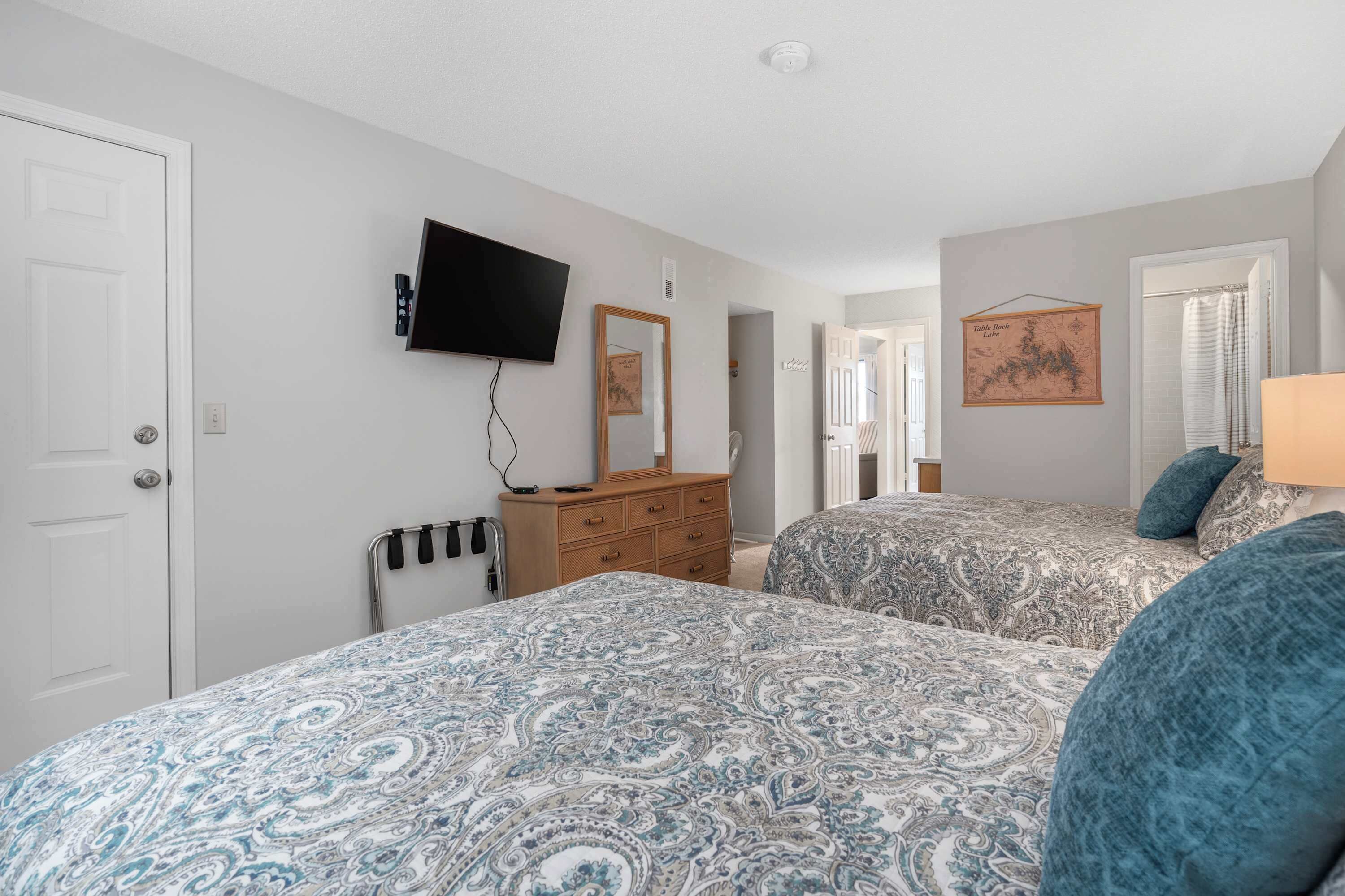 A bedroom with two beds, a dresser, a TV, and a map on the wall.