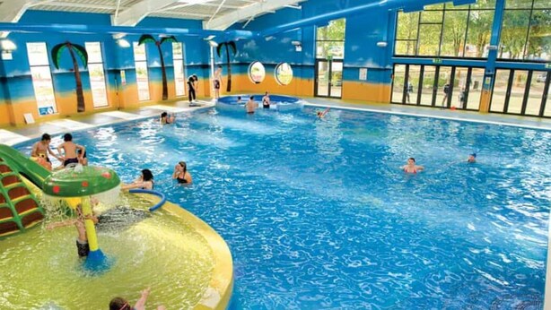 An indoor swimming pool with multiple lanes, a water slide, and a shallow play area. - River Meadows Retreat. Contemporary, spacious caravan. 3 Bedroom, sleeps 8 (Great Billing)