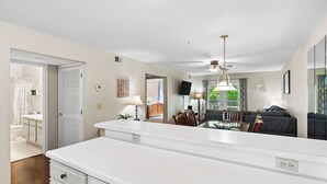 A modern kitchen with a central island, a dining area with a table and chairs, and a living area with a sofa and a TV. - Ron's Retreat Stay for 6 With Resort Amenities (Branson)