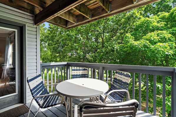 A covered outdoor seating area with a table and chairs, overlooking a lush green landscape.