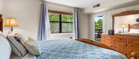 Un dormitorio con cama, cómoda, ventana con cortinas y vistas a espacios verdes.