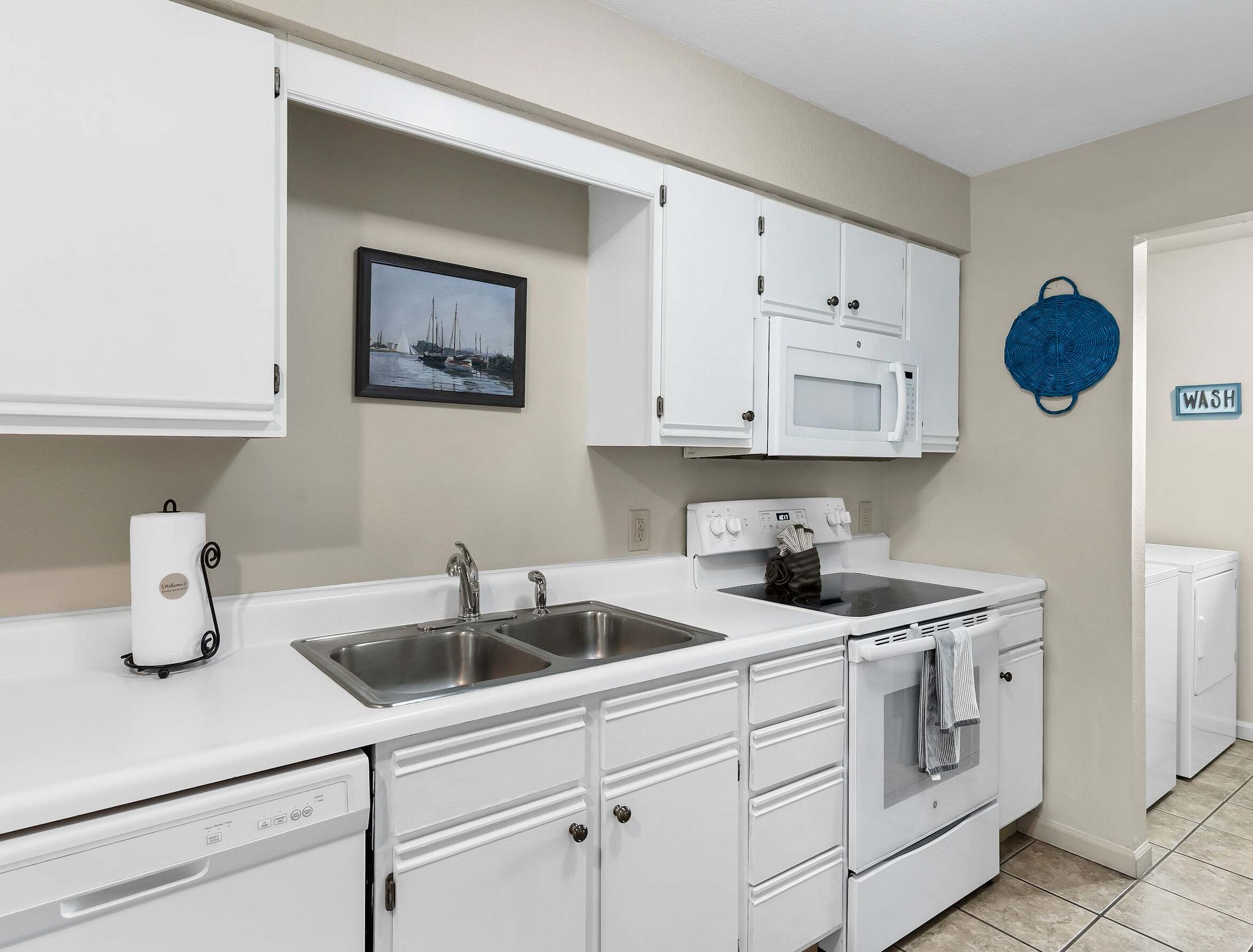 A kitchen with white cabinets, a double sink, a microwave, an oven, and a dishwasher.
