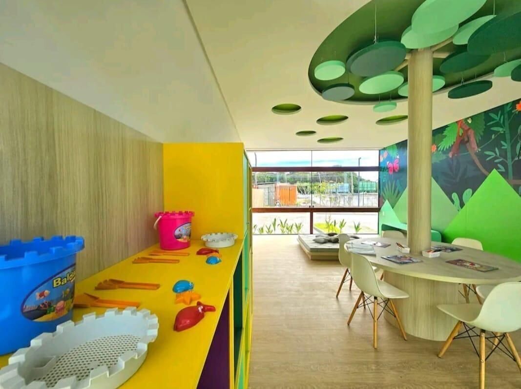 A children's play area with colorful toys, a table with chairs, and a mural on the wall.