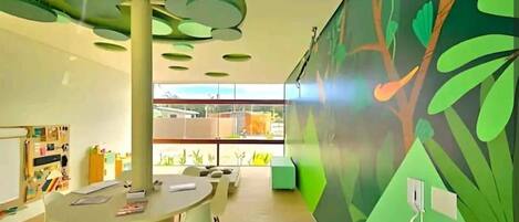 A modern interior with a round table, white chairs, a green accent wall, and a ceiling with circular light fixtures.