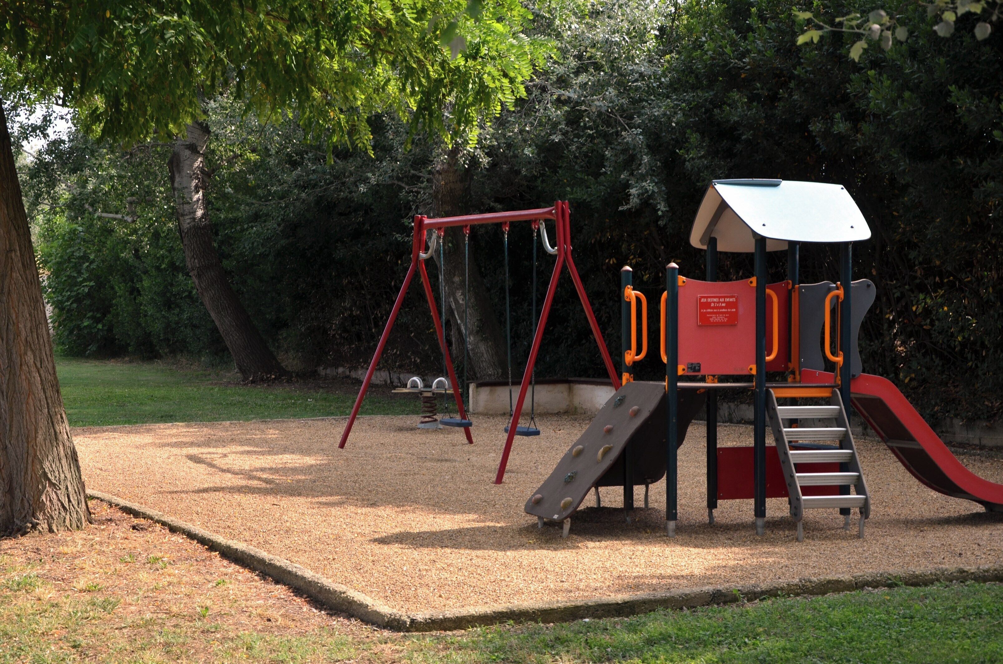 Un parque con columpios, un tobogán y una estructura para escalar.