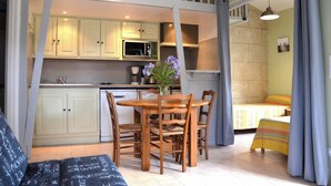 Un espace de vie compact comprenant un coin repas, une kitchenette et un lit.
