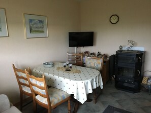 Un coin repas comprenant une table ronde, des chaises, un téléviseur, une horloge et une cheminée.