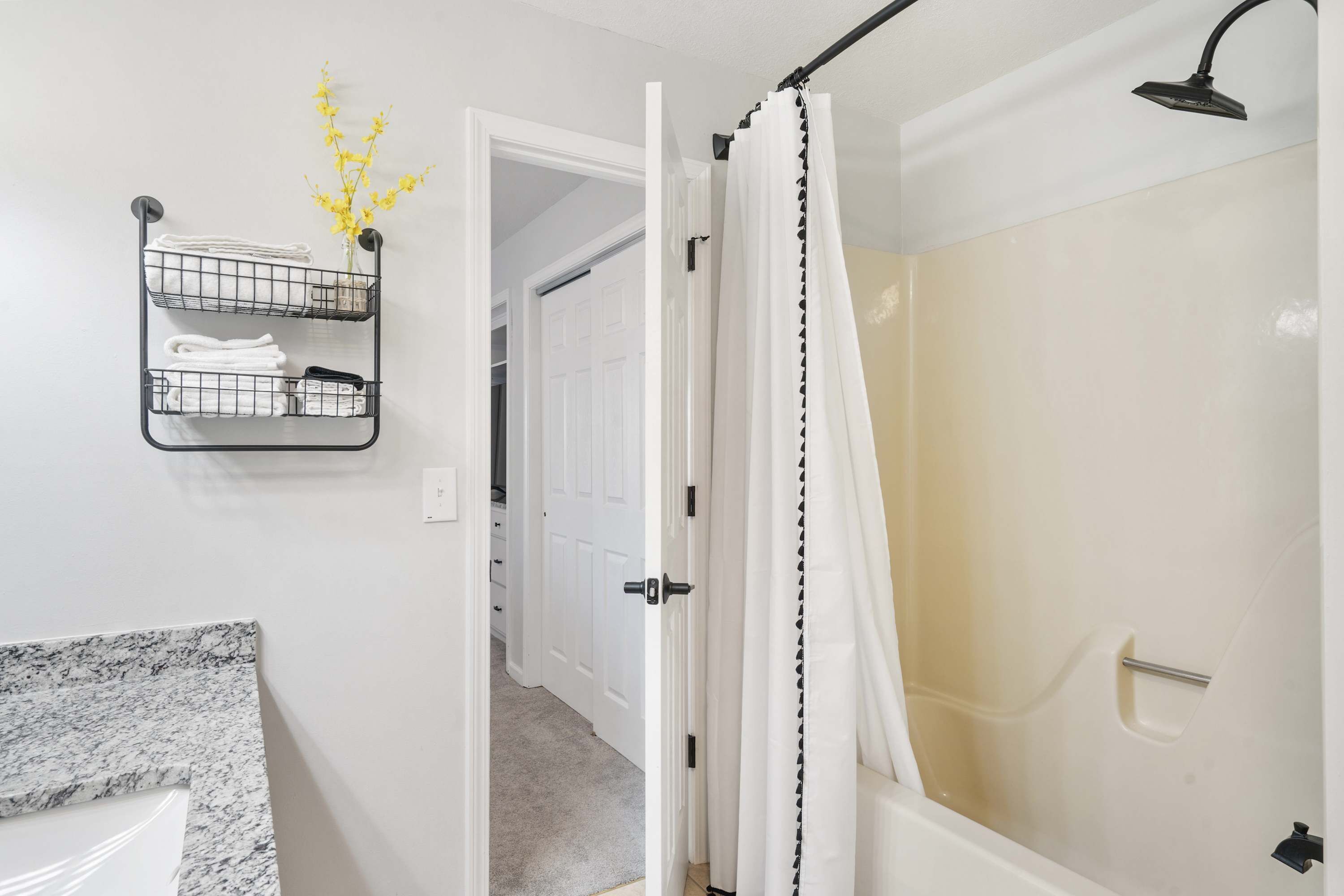 A bathroom with a shower, a towel rack, and a marble countertop.