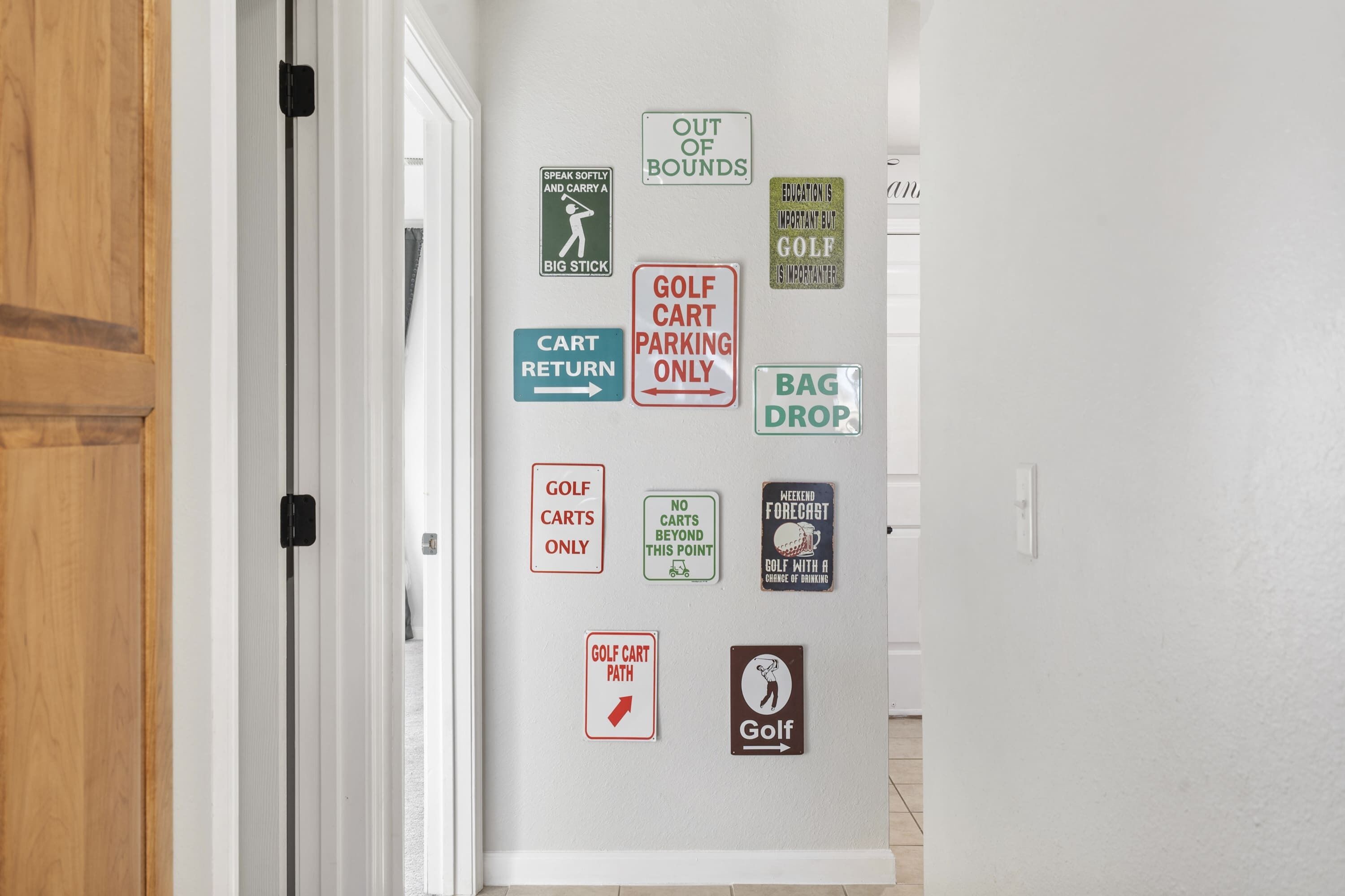A hallway with various signs on the wall, including 'GOLF CART PARKING ONLY', 'OUT OF BOUNDS', and 'GOLF CART RETURN'.