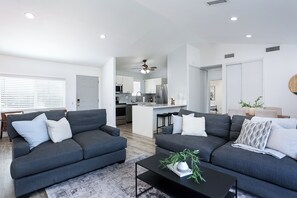 A modern living room with two grey sofas, a black coffee table, and a kitchen in the background. - Modern, Updated House In Santee with Wifi, AC, and Yard (Santee)