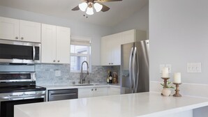 Una cocina moderna con armarios blancos, electrodomésticos de acero inoxidable y una salpicadera de mármol.
