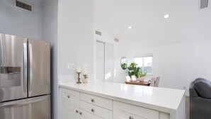 Una cocina moderna con un refrigerador de acero inoxidable, muebles blancos y una isla grande.