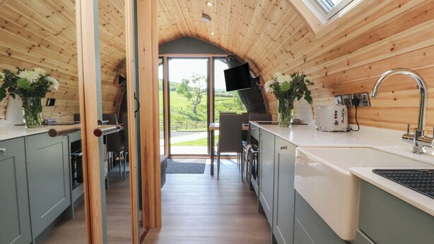 Une cuisine moderne avec des murs en bois, une grande fenêtre et un coin repas offrant une vue sur l’extérieur.