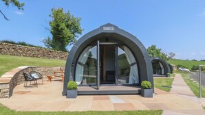 Une villa moderne dotée d’une entrée incurvée, d’un mur en pierre et d’un patio aménagé avec du mobilier d’extérieur.