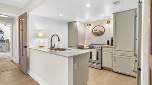 A modern kitchen with a central island, stainless steel appliances, and a light-colored backsplash.