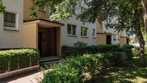 A modern apartment building with a brick entrance, multiple windows, and a well-maintained garden area. - Apartamenty Sun & Snow Kopernika 16 (Ustka)