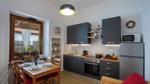 Eine kompakte Küche mit modernen Geräten, ein Essbereich mit Holztisch und -stühlen sowie eine gemütliche Sitzecke.