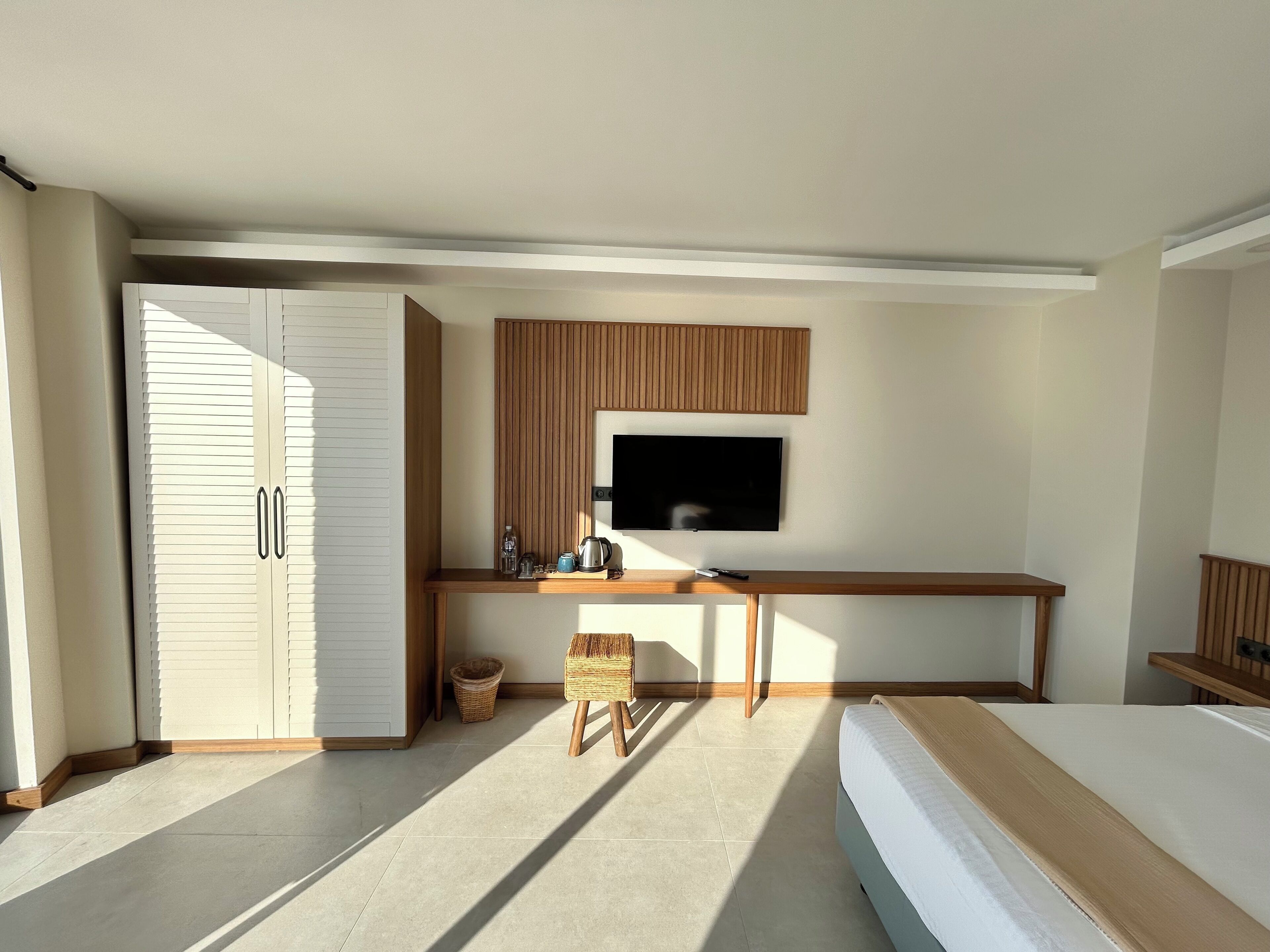Une chambre à coucher moderne, avec un lit, un téléviseur fixé au mur, un bureau avec une chaise et une armoire.