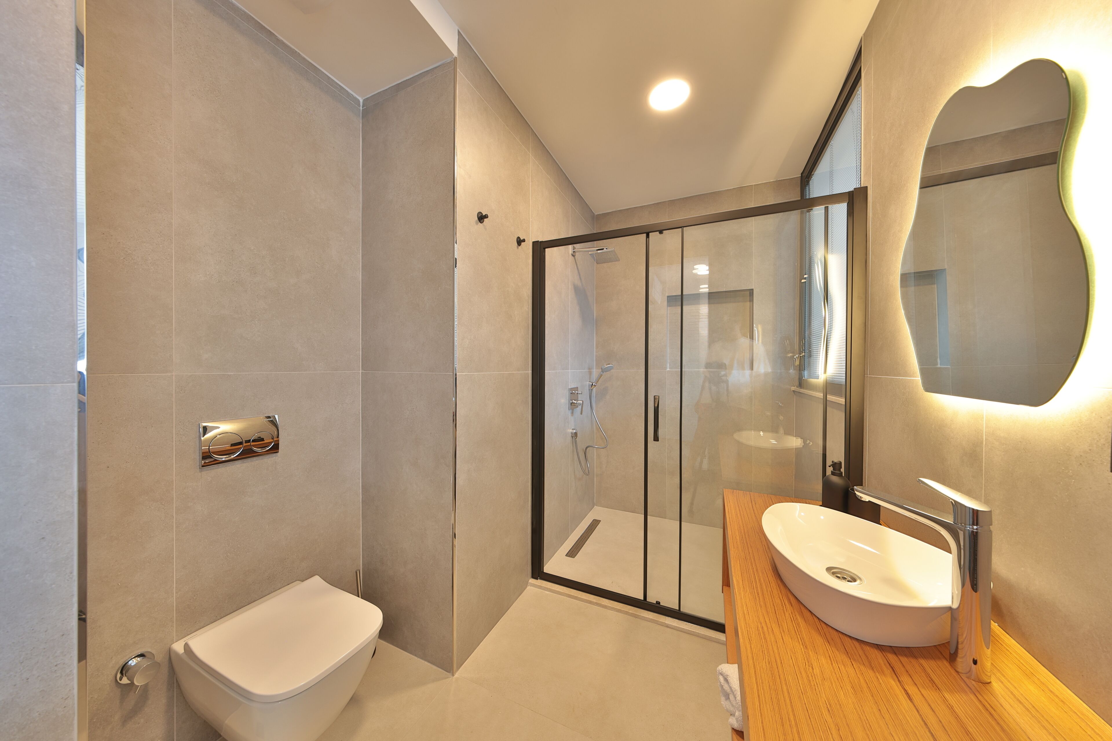 A modern bathroom with a glass-enclosed shower, a white toilet, and a wooden vanity with a sink.