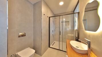 A modern bathroom with a glass-enclosed shower, a white toilet, and a wooden vanity with a sink.