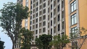 A multi-story building with a uniform facade, a paved walkway, and trees. - Phu Quoc Sea View Apartment (Phu Quoc)