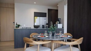 A modern kitchen with a central island, wooden chairs, and a dining table set for two. - City-view condo w/ pool & free parking (Guadalajara)