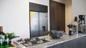 A modern kitchen with a gas stove, stainless steel refrigerator, and a large bowl on the counter. - City-view condo w/ pool & free parking (Guadalajara)