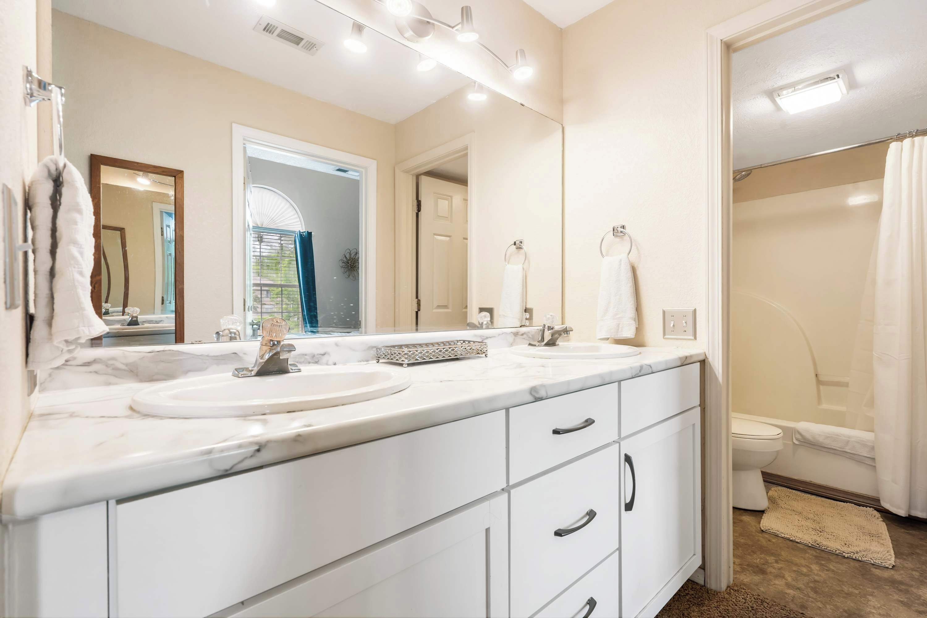A modern bathroom with a double sink vanity, a large mirror, and a shower area.