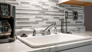 A modern kitchen with a white marble countertop, a built-in coffee maker, and a sleek faucet. - Warm Welcome Getaway Resort Stay for 6 With Amenities Near Downtown (Branson)