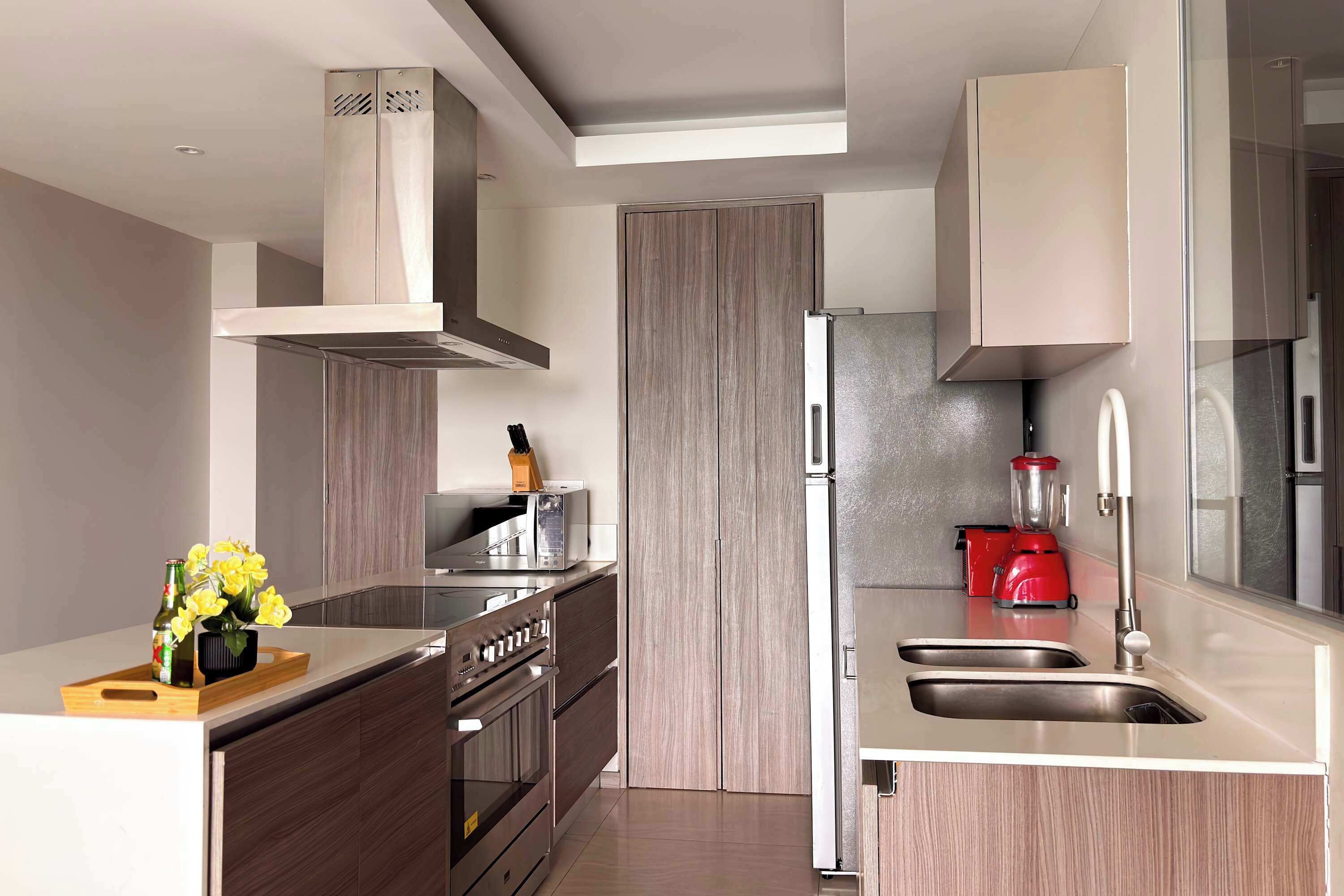 A modern kitchen with a built-in oven, microwave, and a red blender.