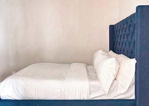 A single bed with a dark headboard and white bedding.