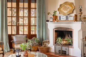 A cozy living room with a fireplace, a comfortable armchair, and various decorative items.