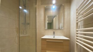 A modern bathroom with a glass-enclosed shower, a sink with a mirror above it, and a towel rack. - Superb studio with sleeping area! Old Nice! (Nice)